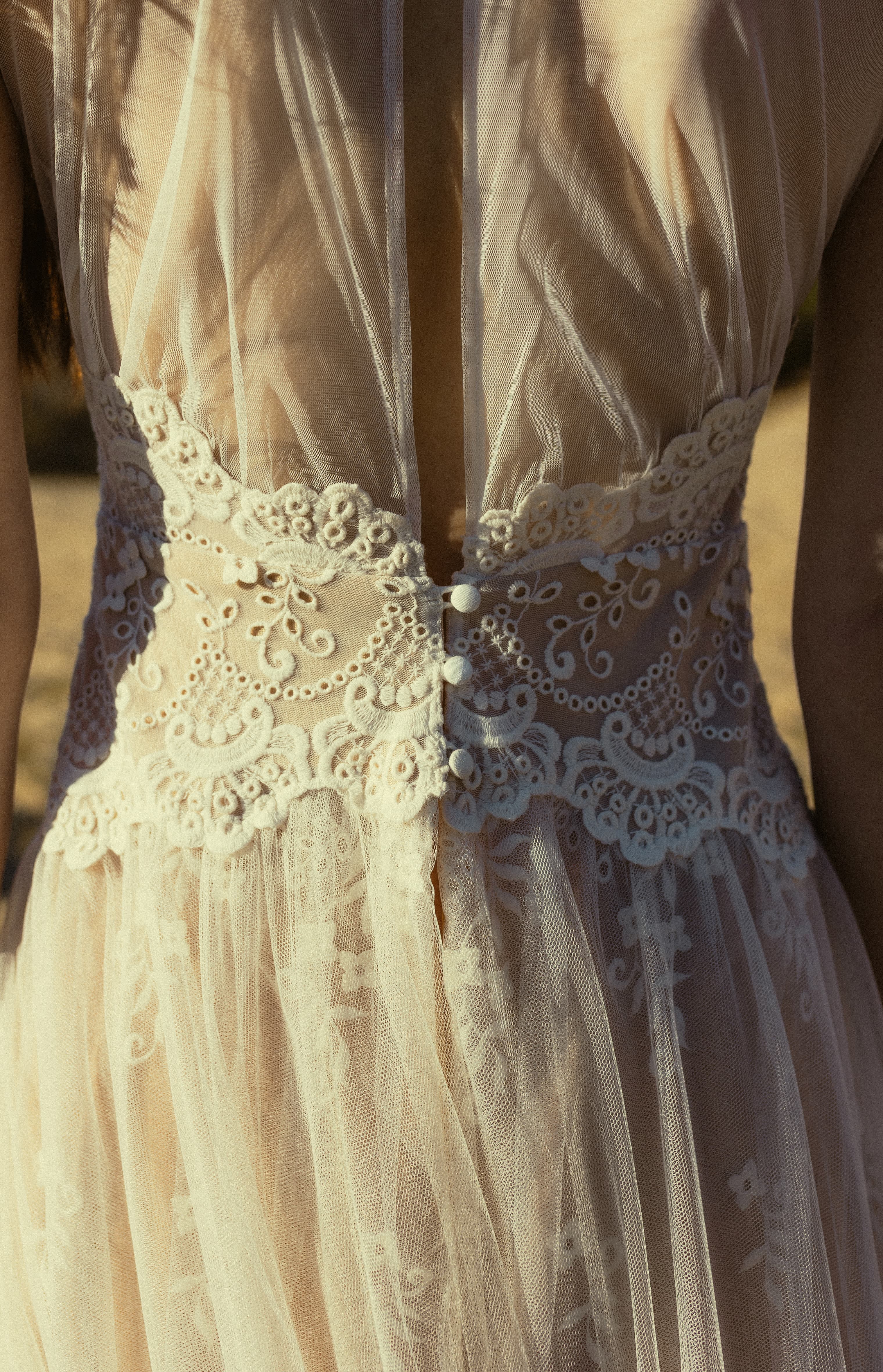 Kant gelaagd op licht. Korte mouwen, geplooide tule rok, transparante rug met fijne details. Kanten manchetten omlijsten elk gebaar. De Priestess beweegt met stille precisie – krachtig, gecentreerd, stralend.